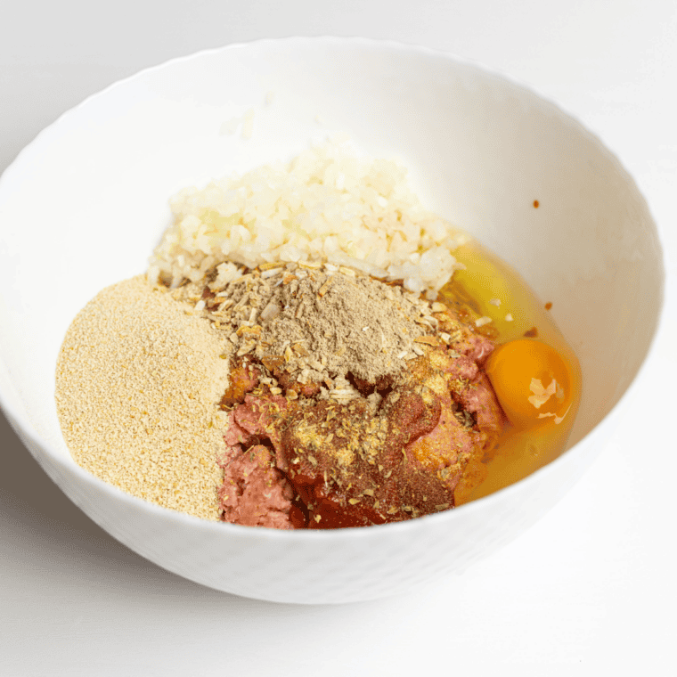 Ground beef, eggs, milk, breadcrumbs, and copycat McCormick meatloaf seasoning in a bowl