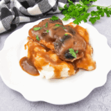 Copycat McCormick turkey gravy poured over a plate of creamy mashed potatoes