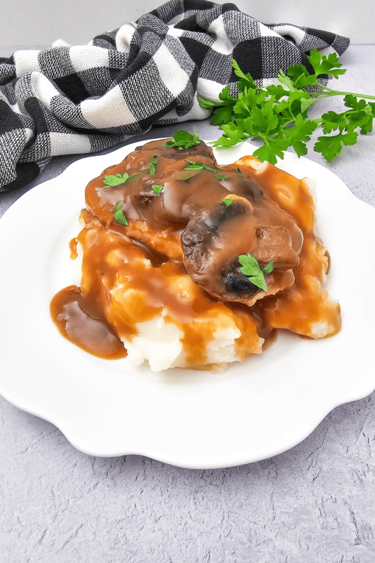 Turkey gravy ladled over mashed potatoes on a white dinner plate