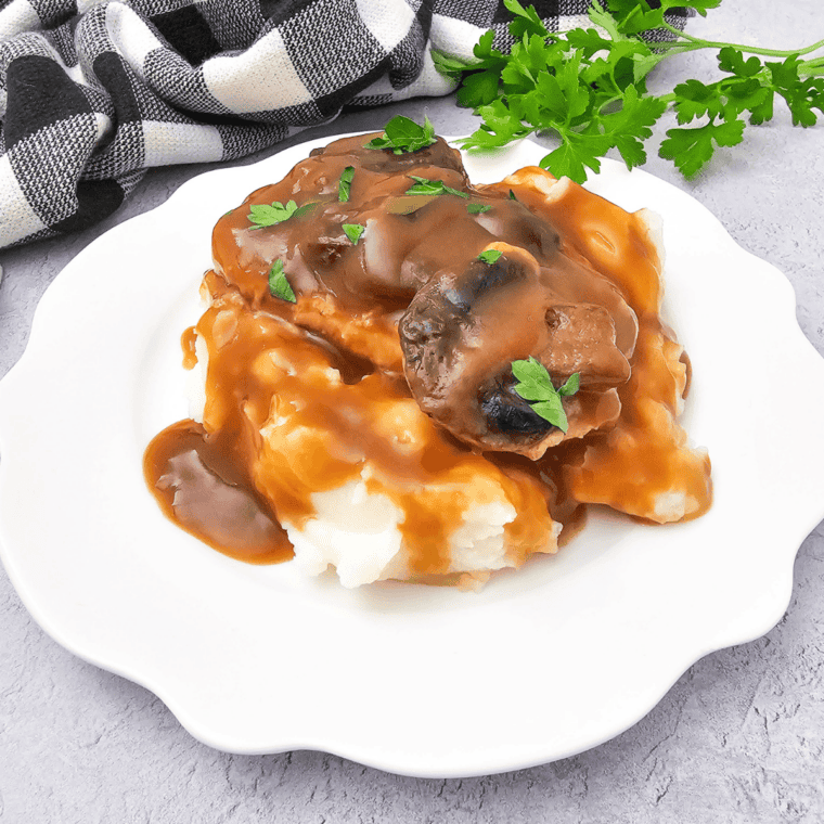 Copycat McCormick turkey gravy poured over a plate of creamy mashed potatoes