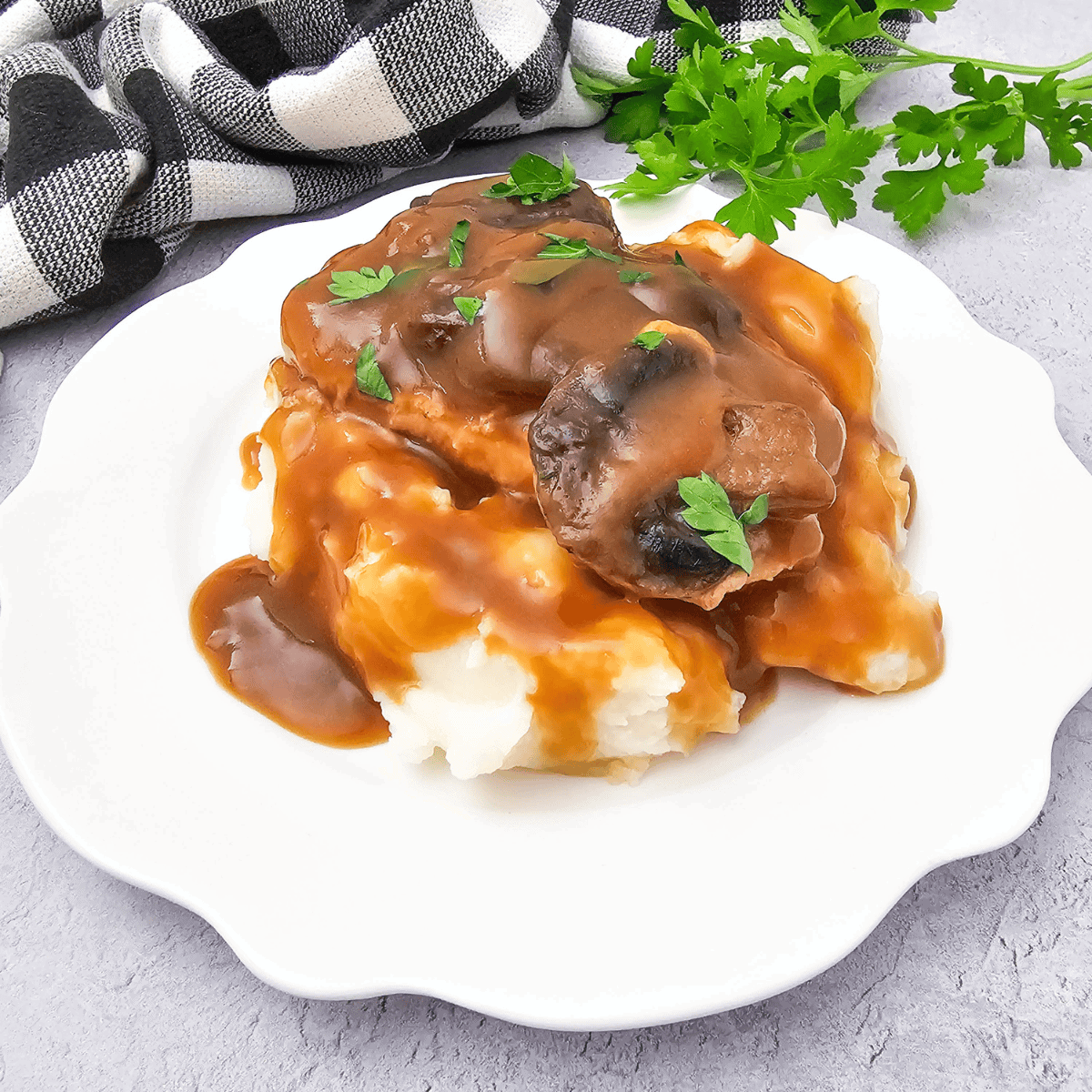 Copycat McCormick turkey gravy poured over a plate of creamy mashed potatoes