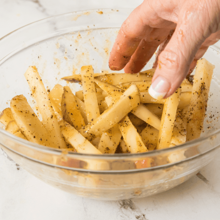 Potato fries tossed with cornstarch, oil, and Aussie fries seasoning blend of paprika, garlic powder, and cayenne in a large bowl