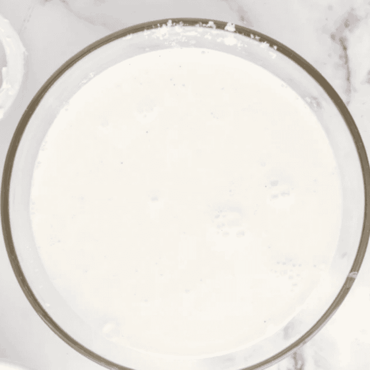 Whisking whole milk and sweetened condensed milk in a glass measuring cup for a copycat Wendy's Frosty-ccino