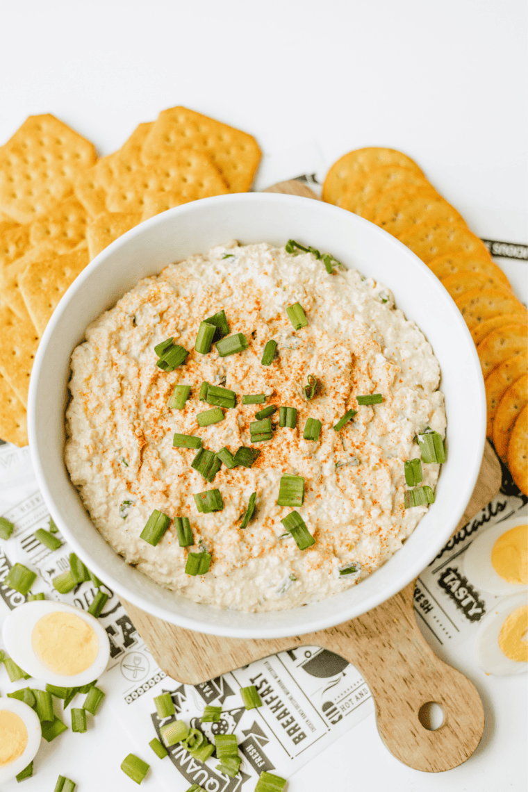 Bowl of creamy deviled egg dip topped with paprika and chopped green onions
