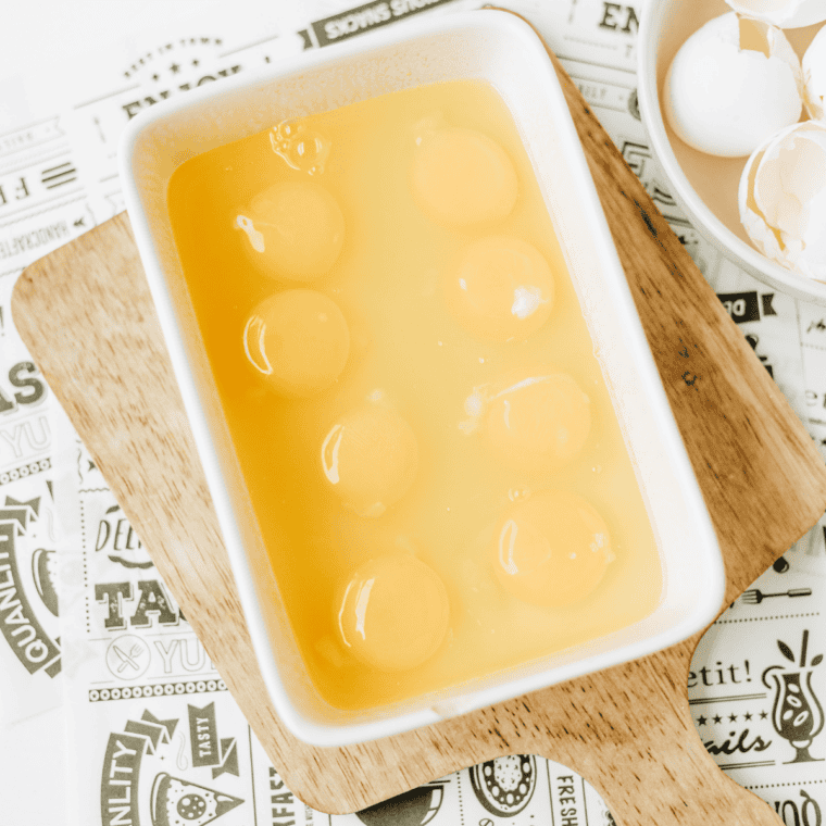Eight raw eggs cracked into a greased bread pan set inside a casserole dish water bath