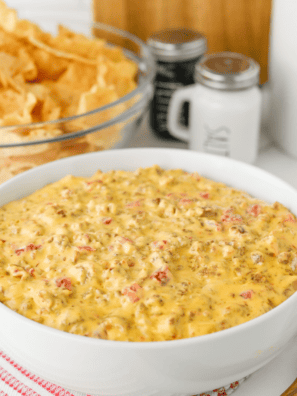 Bowl of football dip on a game day snack table with chips, wings and cold drinks