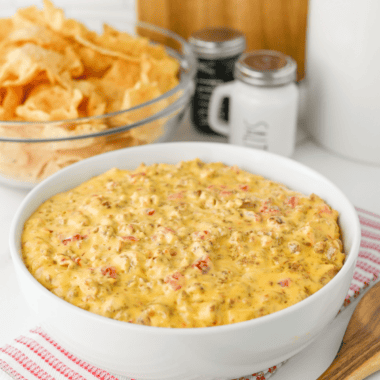 Bowl of football dip on a game day snack table with chips, wings and cold drinks