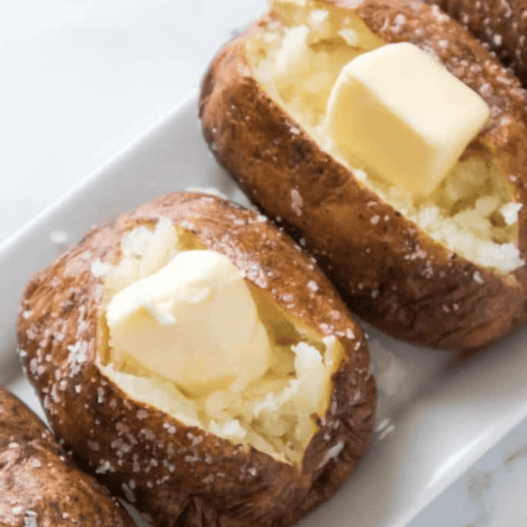 Baked potato split lengthwise and squeezed open so the flesh mounds up