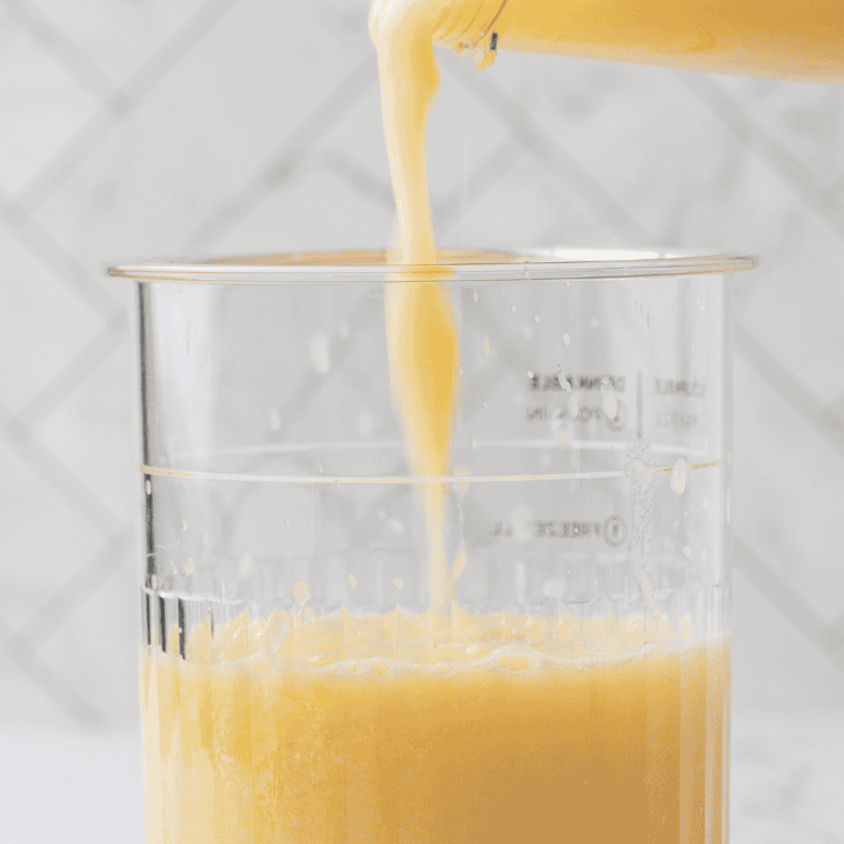 Pouring canned pineapple chunks and juice into a blender for Ninja Creami Dole Whip