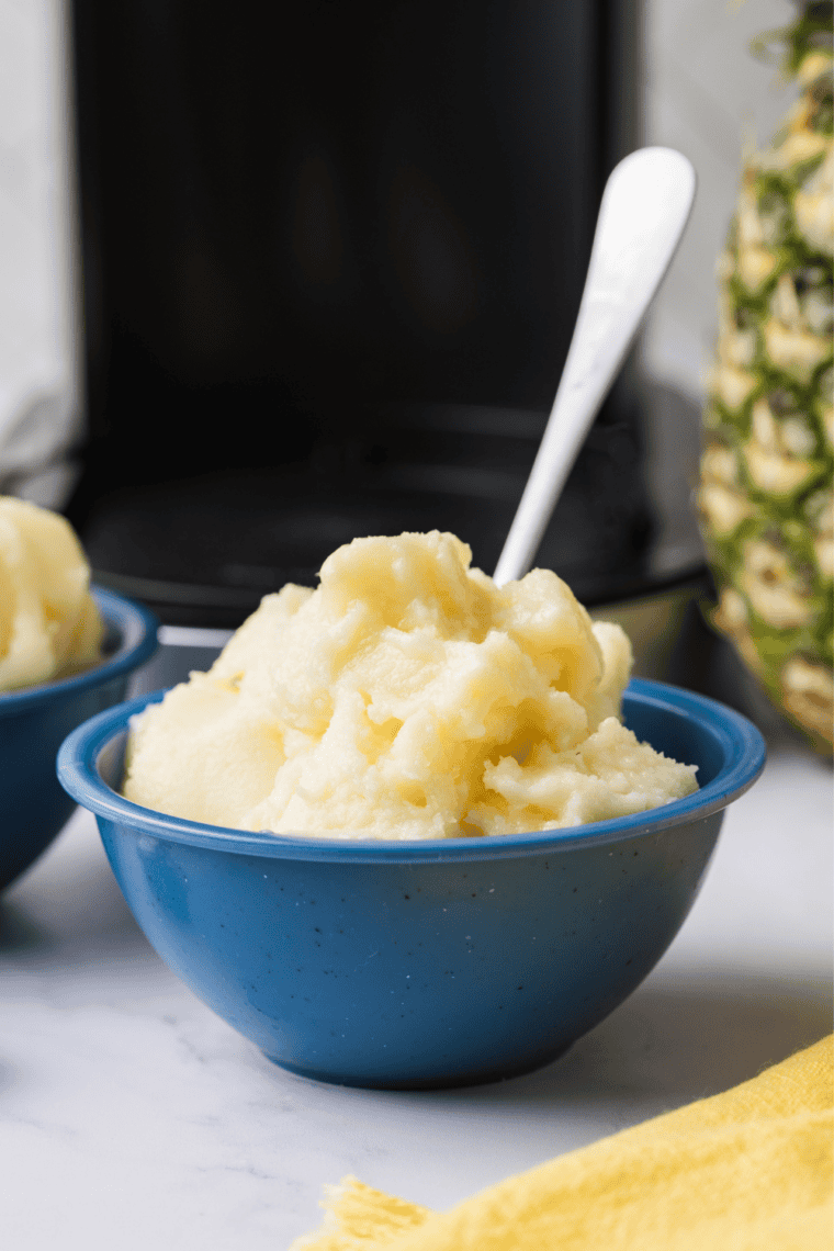Ninja Creami Dole Whip swirled in a glass bowl, topped with a fresh pineapple wedge