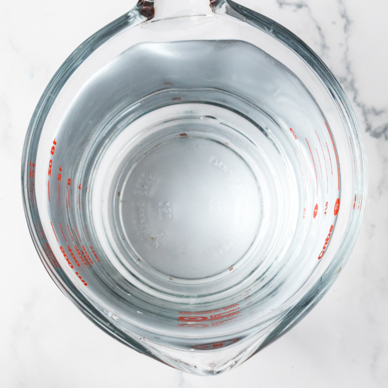 Stirring granulated sugar and salt into warm water in a glass measuring cup until dissolved