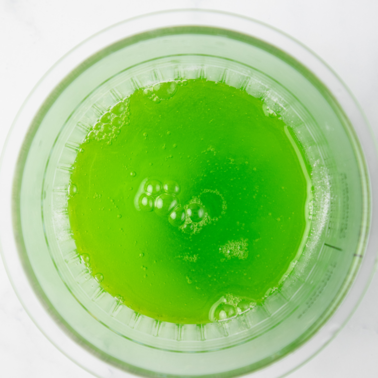 Pouring fresh lime juice and zest into the sweetened water and stirring to combine