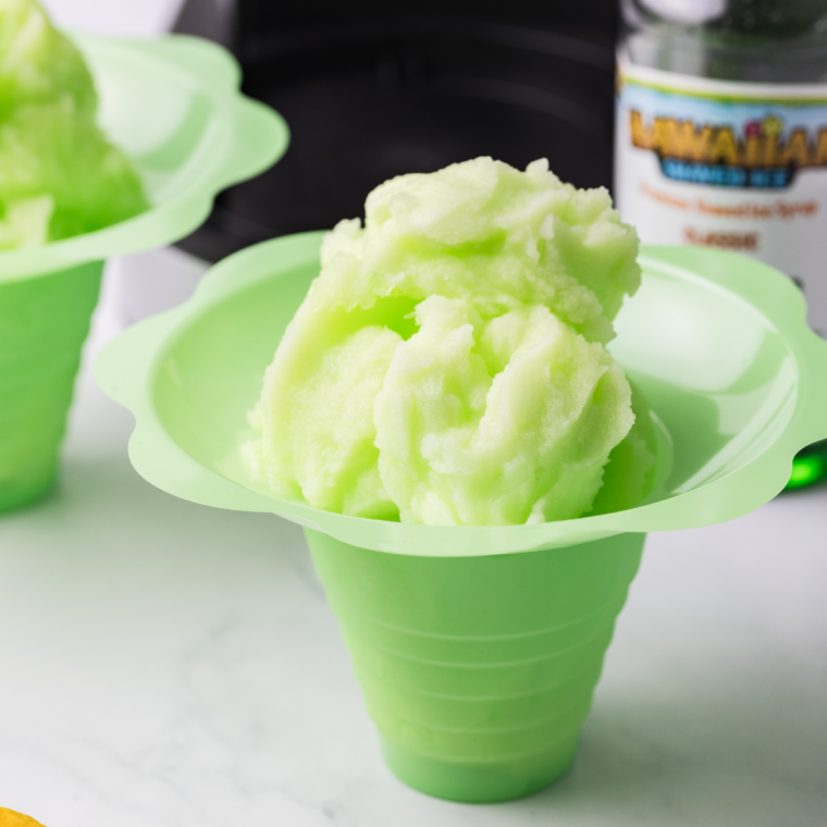 Bright green lime Italian ice scooped into a small white bowl with a lime wedge
