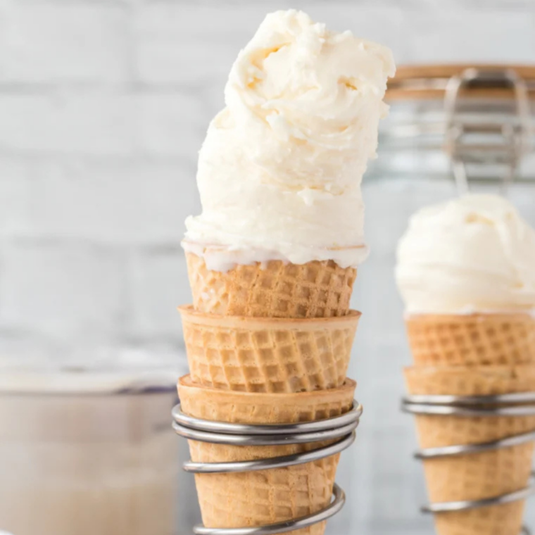 Homemade Ninja Creami ice cream scooped into three waffle cones on a marble counter