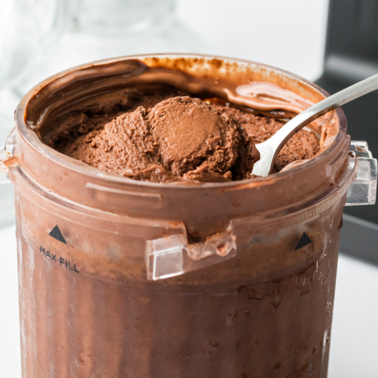 Ninja Creami pint container seated in the outer bowl with the lid beside it