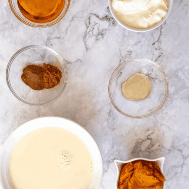 Ingredients for a copycat pumpkin pie Blizzard on a table &mdash; heavy cream, milk, sugar, cream cheese, vanilla, and a slice of pumpkin pie