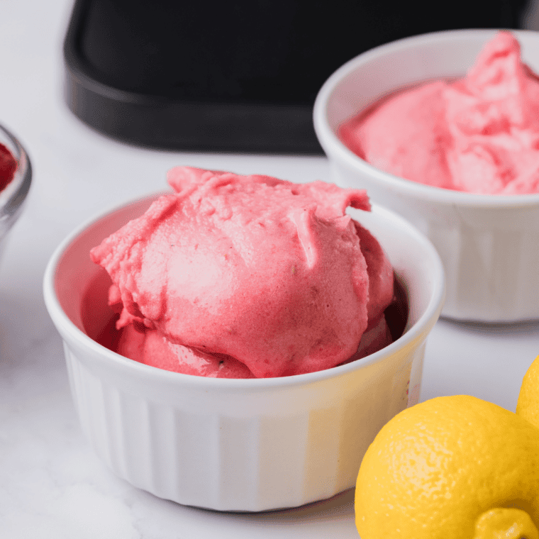 Ninja Creami raspberry lemonade sorbet in a bowl topped with fresh raspberries