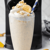 Thick Ninja Creami Steak 'n Shake banana shake in a tall glass topped with whipped cream and a maraschino cherry