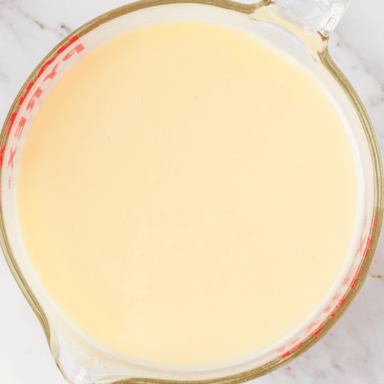 Banana shake base being whisked together in a mixing bowl with milk, cream, and vanilla