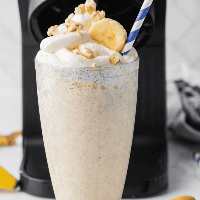 Overhead view of a creamy banana shake topped with whipped cream on a marble counter