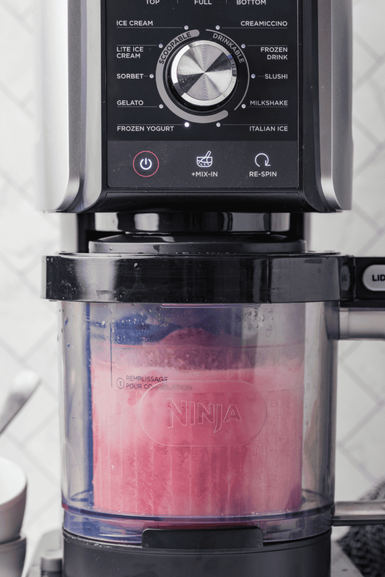 Pink strawberry yogurt base poured into a Ninja Creami pint up to the max fill line