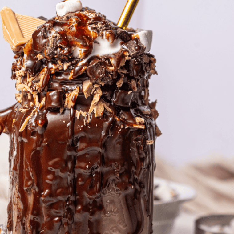 Tall glass of Ninja Creami milkshake topped with whipped cream and a straw