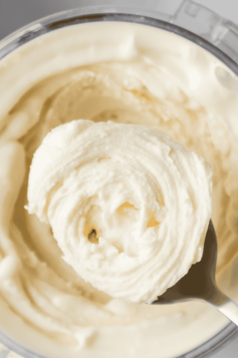 Bowl of ice cream next to a Ninja Creami with the pint container still in the outer bowl