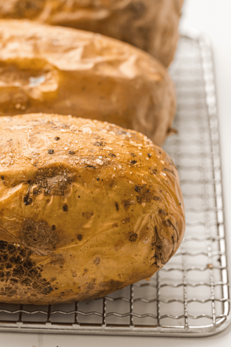Baked potatoes resting on a cooling rack after air frying in the Ninja Crispi