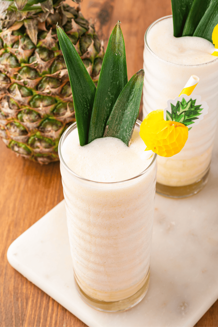 Frozen pineapple Dole Whip slush in a ribbed glass beside a fresh pineapple