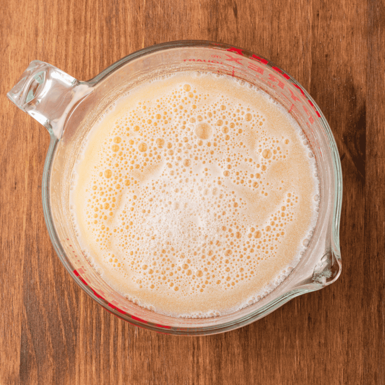 Dream Whip powder being whisked into a measuring cup of pineapple juice