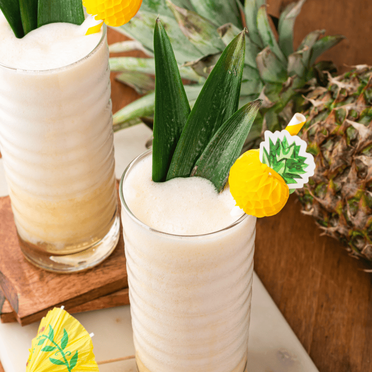 Creamy pineapple Dole Whip drink beside a fresh pineapple on a marble board