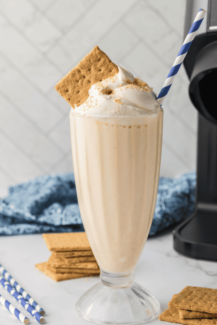 Close-up of a pumpkin milkshake with whipped cream, cinnamon, and a striped straw