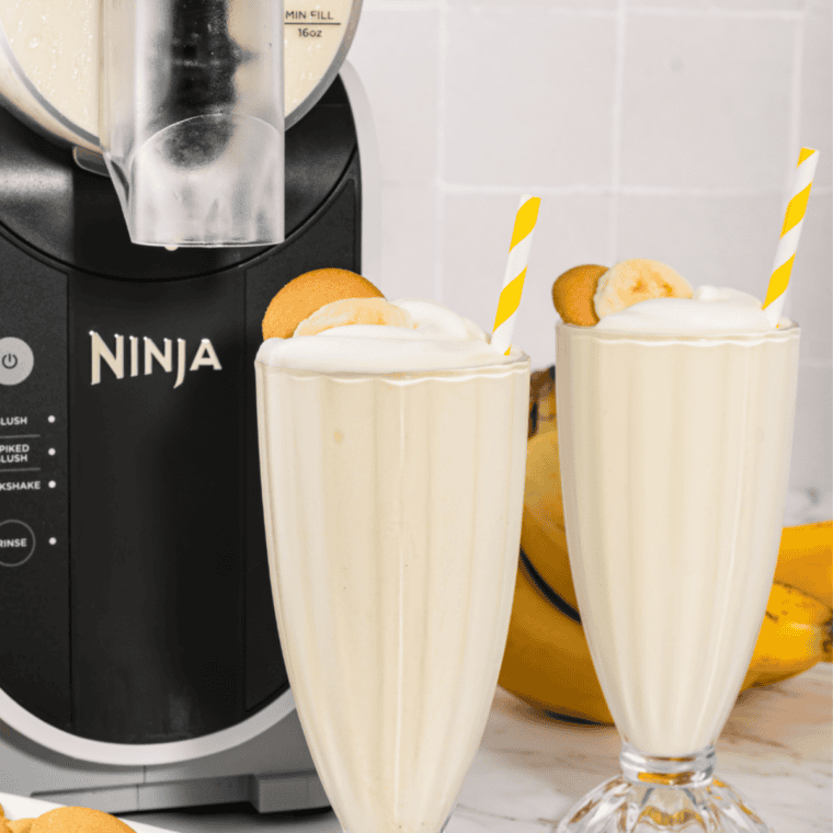 Two glasses of homemade Ninja Slushi vanilla milkshake with striped straws on a marble counter