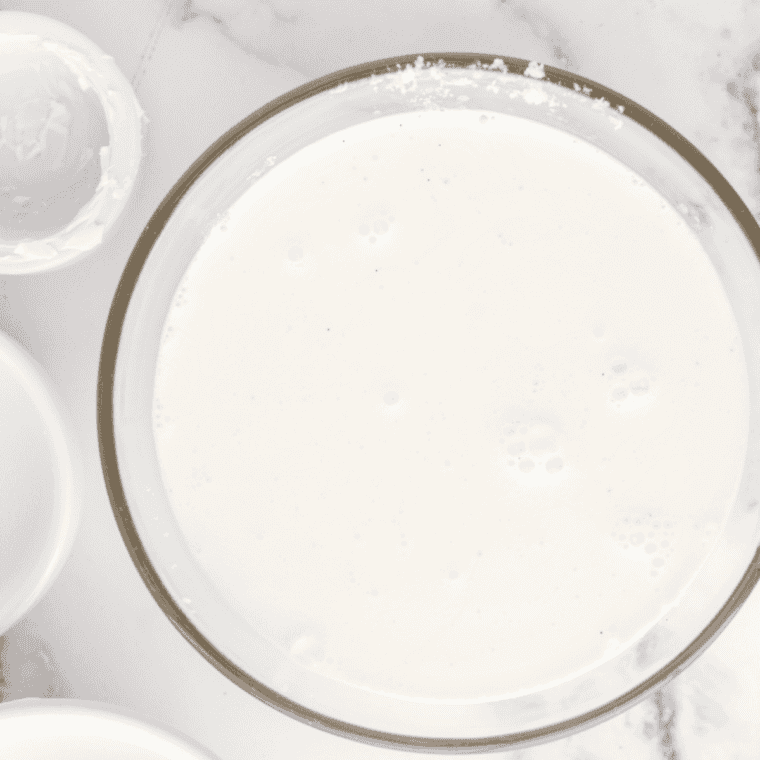 Whisking granulated sugar and salt into whole milk in a glass pitcher until dissolved