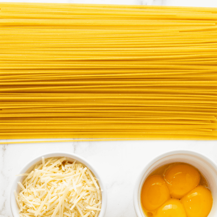 Spaghetti, butter, block of aged mizithra cheese and parsley on a wooden board