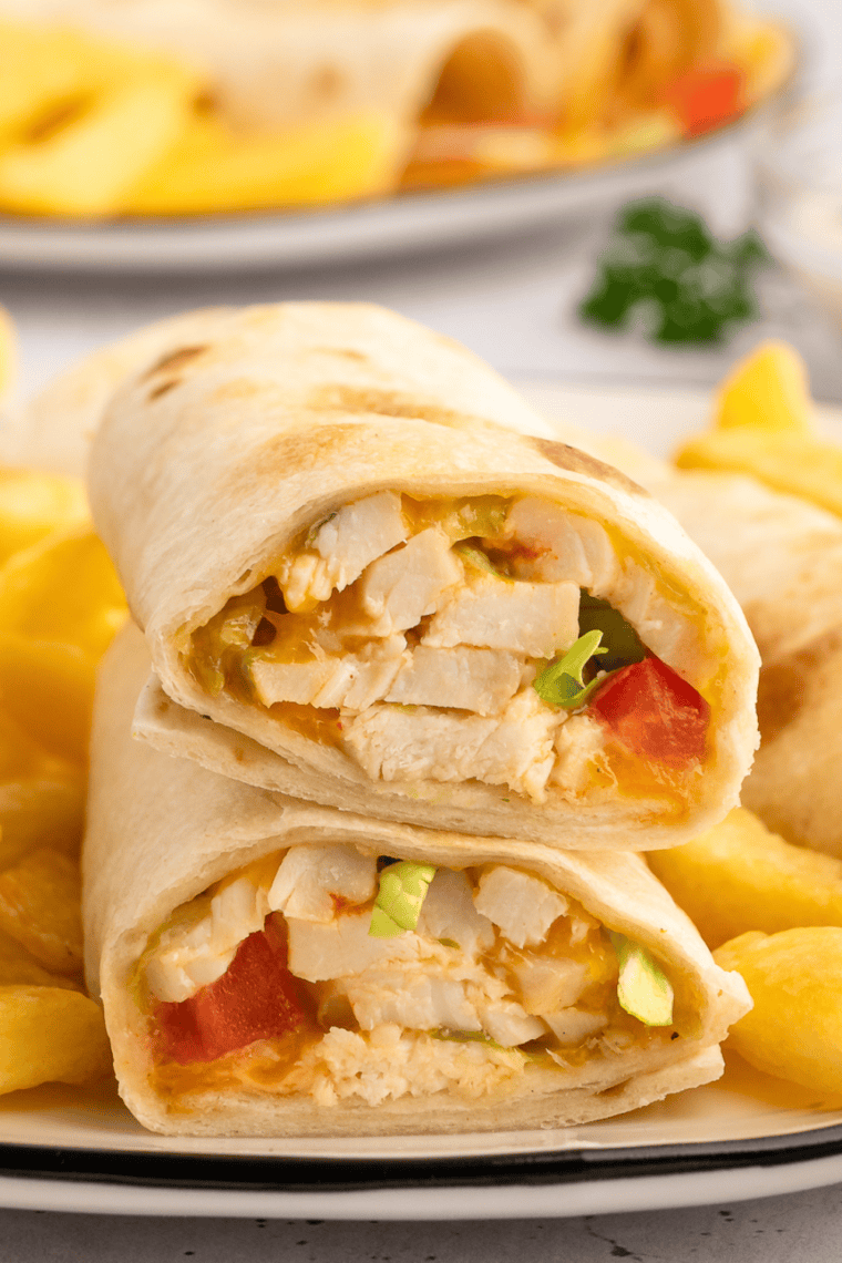 Rotisserie chicken snack wrap cut in half showing shredded chicken, ranch, and melted cheddar inside a crispy golden tortilla