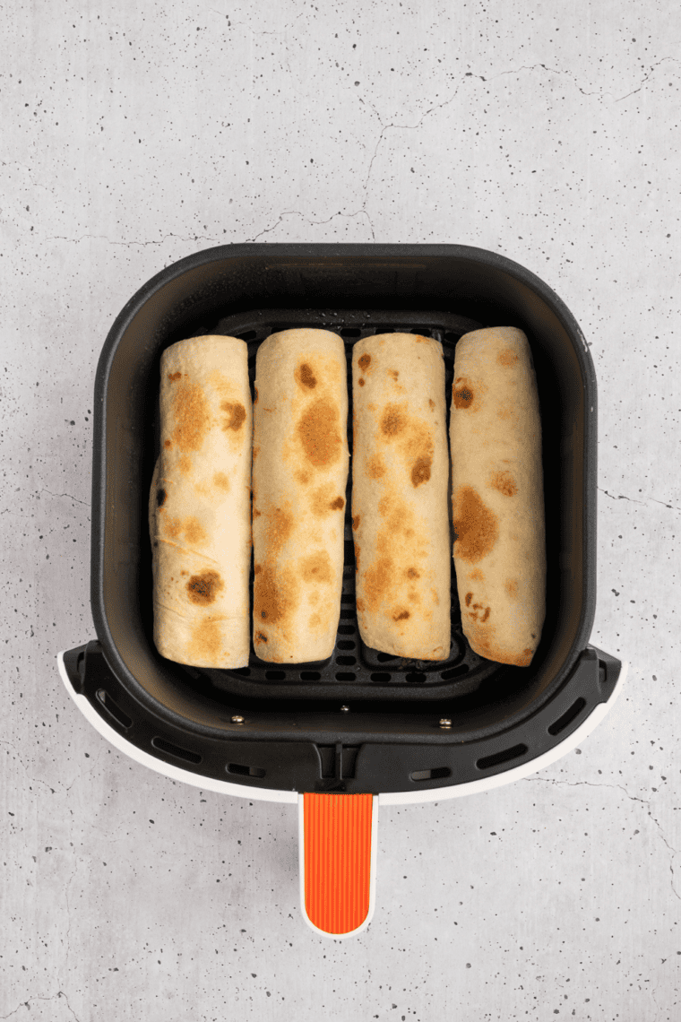 Golden brown air fryer snack wraps in the basket after cooking