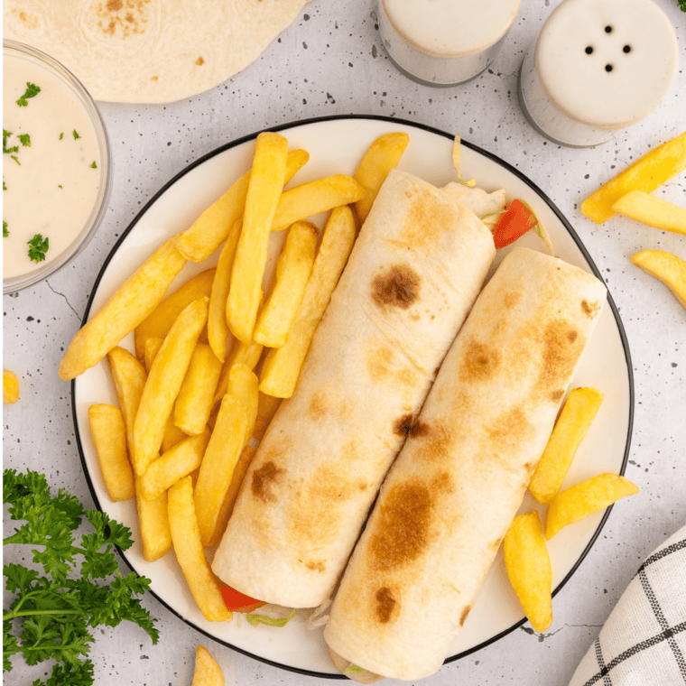 Rotisserie chicken snack wrap cut in half showing shredded chicken, ranch, and melted cheddar inside a crispy golden tortilla