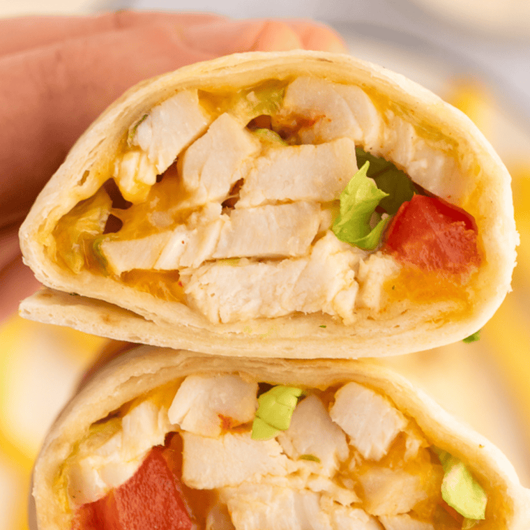 Hand holding a rotisserie chicken snack wrap with melted cheddar pulling away at the bite