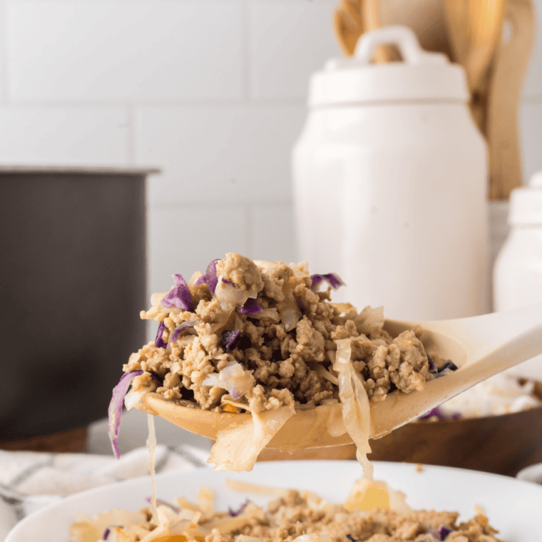 Close-up of slow cooker chicken egg roll in a bowl with a drizzle of sriracha mayo and chopsticks resting on the rim