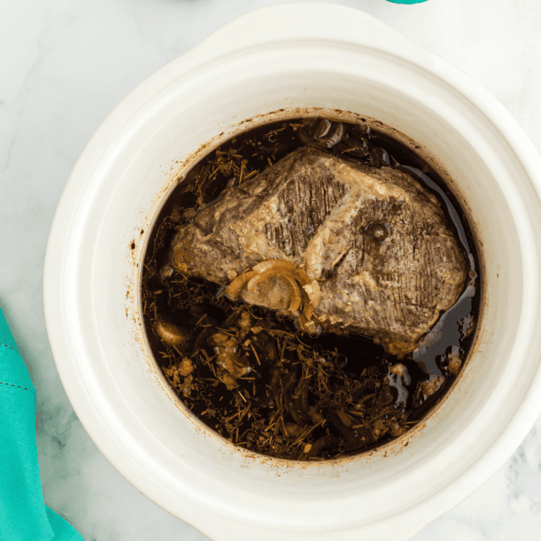 Instant-read thermometer inserted into the thickest part of a cooked tri tip in a slow cooker