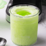 Bowl of sugar-free Ninja Creami lemon Italian ice with a lemon wedge