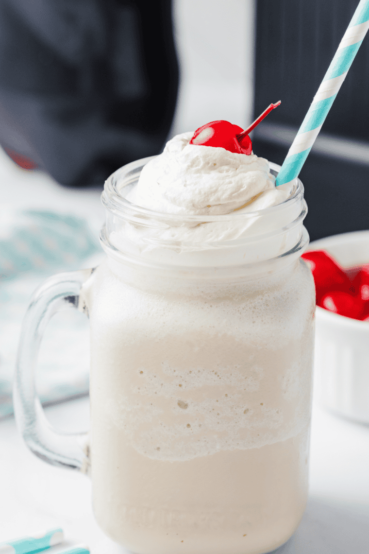 Thick Ninja Creami milkshake in a tall glass with whipped cream and a straw