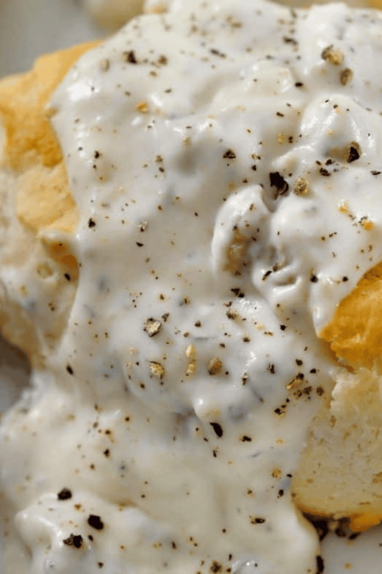 Split biscuits smothered in homemade country gravy on a white plate