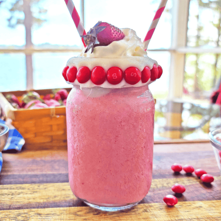 Ninja Creami strawberry milkshake ice cream scooped into a white bowl with fresh strawberries on top