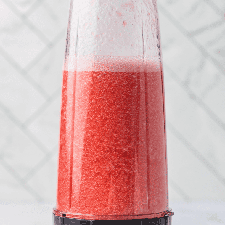 Straining strawberry purée through a fine-mesh sieve to remove seeds before churning