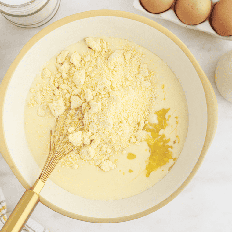 Whisking eggs, milk, sugar, and flour in a bowl for corn pudding custard
