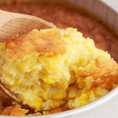 12 Bones Smokehouse copycat corn pudding in a baking dish with a golden top and one scoop removed