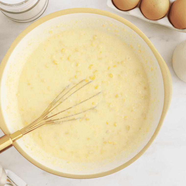 Stirring corn pur&eacute;e, whole kernels, melted butter, and cheddar into the custard mixture