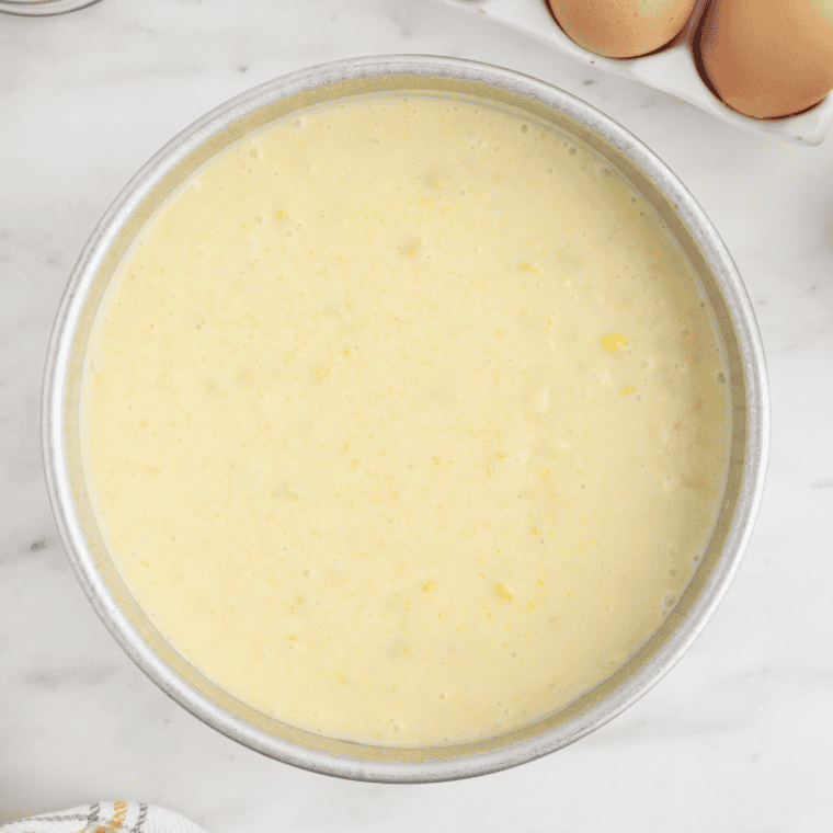 Unbaked corn pudding batter poured into a buttered 9x13 baking dish before going in the oven